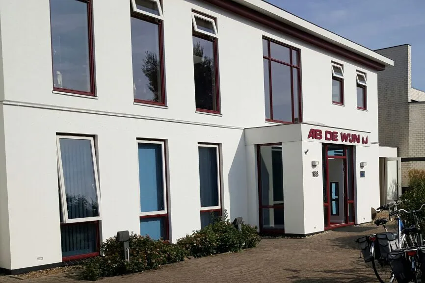 Wit bedrijfspand met donkerrode kozijnen, strak in de verf