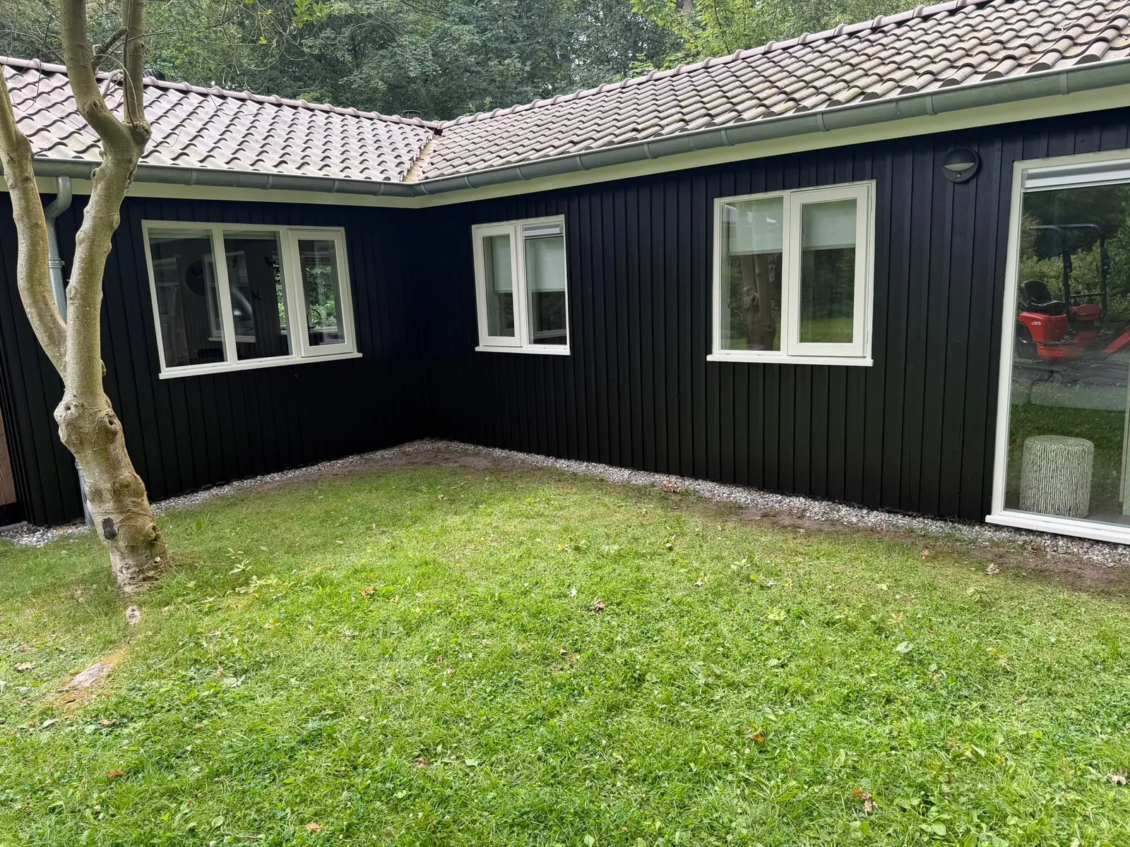 Woning met zwart geschilderde houten gevel en witte kozijnen aan een grasveld